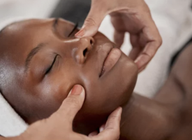 kvinna får ansiktsbehandling, händer masserar kvinnas ansikte